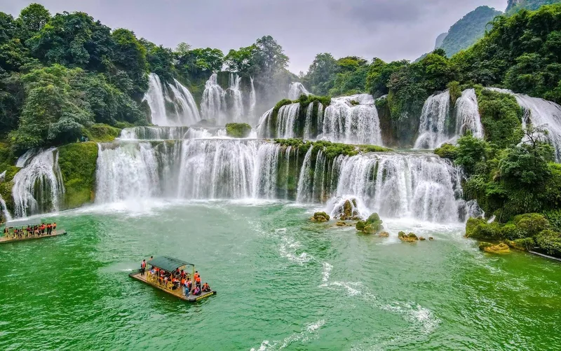 Tourists on bamboo rafts float below the multi-tiered cascades of Ban Gioc Waterfall in Cao Bang.