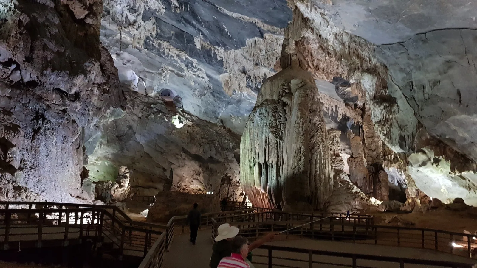 Visitors walk a wooden boardwalk beneath giant stalactites and stalagmites inside Phong Nha cave.