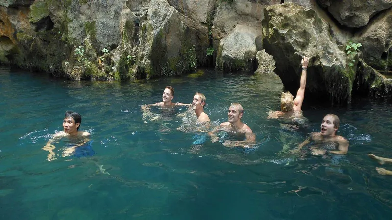 Travelers swim together in a turquoise pool inside a limestone cave at Phong Nha-Ke Bang.