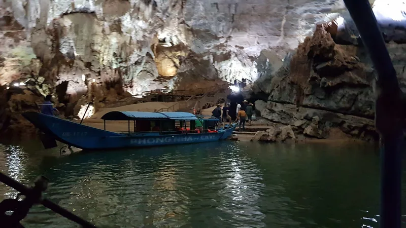 A blue boat labeled Phong Nha Cave carries tourists through the illuminated limestone cavern at Phong Nha Cave.